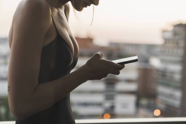 Close-up of young woman wearing black dress using cell phone on balcony model released Symbolfoto  KKAF01452