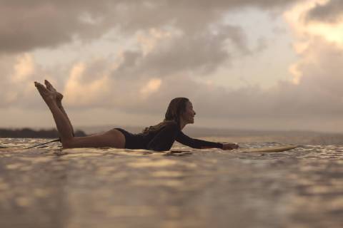 Female surfer lying on surfboard while surfing in ocean at dawn, Kuta, Bali, Indonesia, Kuta Bali Indonesia TRKO022967 model released Symbolfoto Copyright: KonstantinxTrubavin TRKO022967