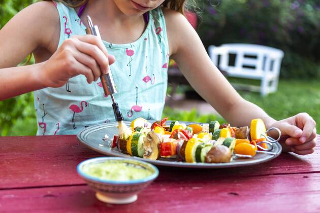young girl spreading vegetarian grill skewers with Argentinian chimichurri model released Symbolfoto  SARF03933