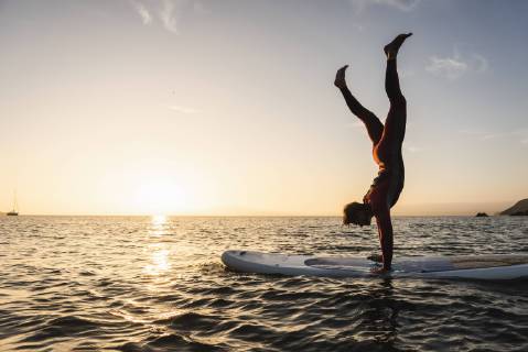 Young man doing handstand on paddleboard at sunset model released Symbolfoto  UUF15085