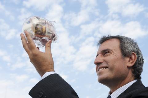 Mature man holding up transparent piggy bank filled with euros  Copyright: OdilonxDimier B07831321
