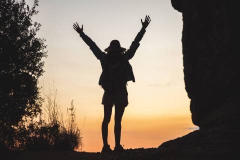 Rear view of woman on a hiking trip raising her arms at sunset model released Symbolfoto  AFVF01585