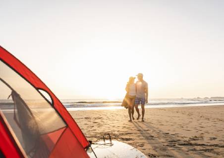 Romantic couple camping on the beach, doing a beach stroll at sunset model released Symbolfoto  UUF15150