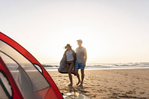 Romantic couple camping on the beach, doing a beach stroll at sunset model released Symbolfoto UUF15151