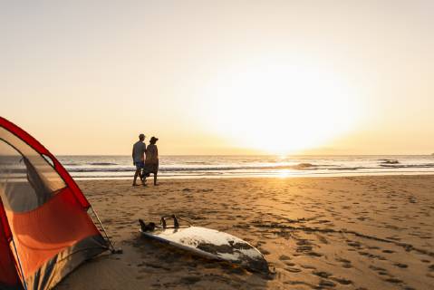 Romantic couple camping on the beach, doing a beach stroll at sunset model released Symbolfoto UUF15154