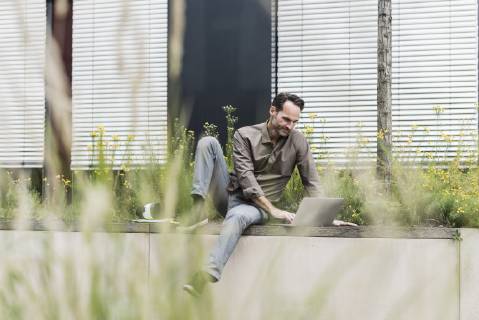 Portrait of smiling businessman working with laptop outdoors model released Symbolfoto property released  UUF12113
