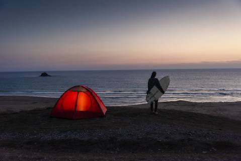 Young woman camping on the beach, carrying surfboard at night model released Symbolfoto  UUF15166
