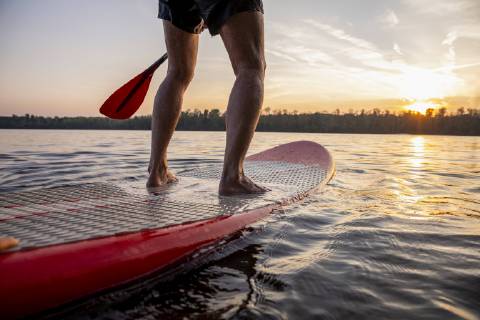 Legs of man standing on paddleboard at sunset model released Symbolfoto  FMKF05242