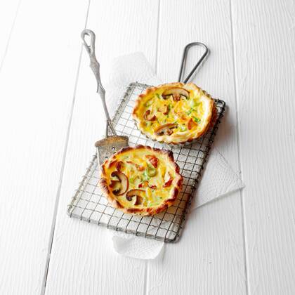  High Angle View of Two Individual Quiche Pies with Mushrooms on Wire Baking Cooling Rack with Metal Lifter on White Wooden Background  Copyright: xfoodandmorex Panthermedia15953837