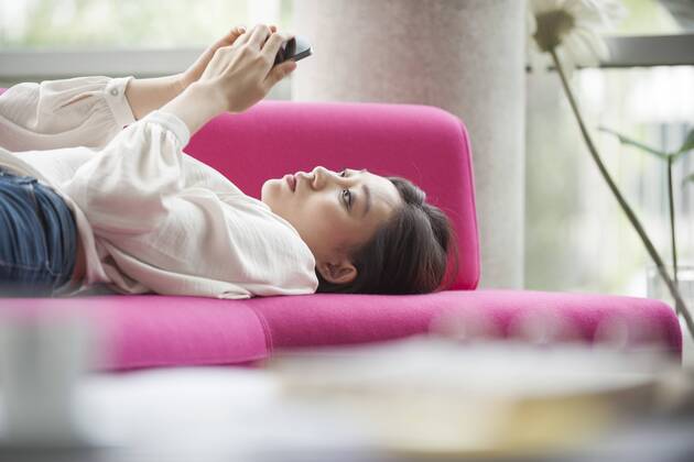 Woman relaxing at home using smartphone  Copyright: OdilonxDimier B27279227