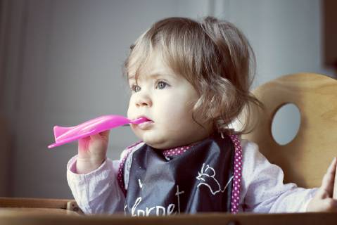 Baby girl feeding herself Copyright: Anne-SophiexBost B49683221