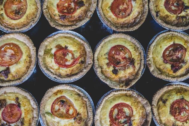 High angle close up of freshly baked quiches with a cheese and tomato topping. High angle close up of freshly baked quiches with a cheese and tomato topping.  44341