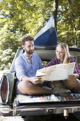 Smiling young couple with map and canoe in car at a brook model released Symbolfoto  FKF02799
