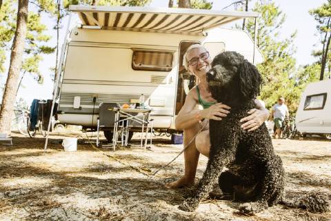 Woman crouches laughing with her dog king poodle in front of camper on a camping site le Gurp Grayan et l Hopital Aquitanien Gironde France Europe Copyright: imageBROKER/JanxTepass ibxjte04831210.jpg