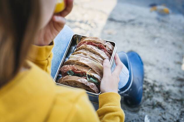 IMAGO Creative: Gesellschaft, Schule, Schulanfang Lifestyle, Haushalt, Küche, nachhaltig und plastikfrei Girl with lunch box sitting on the beach in autumn model released Symbolfoto  HMEF00082