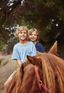 Portrait of two happy boys on horse in a forest model released Symbolfoto  SSCF00092
