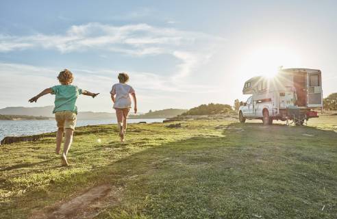 Chile, Talca, Rio Maule, two boys running on meadow beside camper at lake model released Symbolfoto property released  SSCF00125