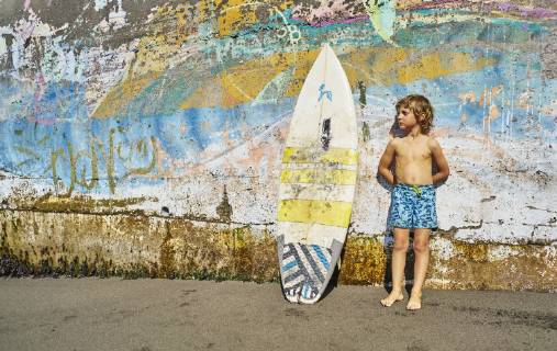 Chile, Pichilemu, boy standing at a colorful wall with surfboard model released Symbolfoto  SSCF00123