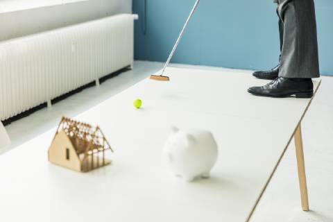 Close-up of businessman playing golf with piggy bank and house model on table in office model released Symbolfoto property released  MOEF01396