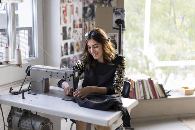 Smiling young fashion designer using sewing machine in her atelier model released Symbolfoto property released  AFVF02054