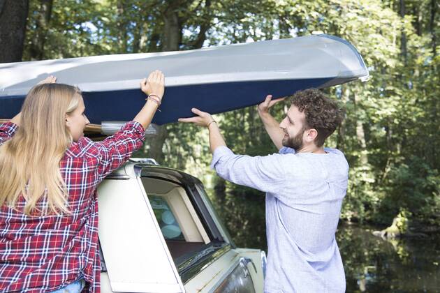Smiling young couple taking canoe from car roof model released Symbolfoto  FKF02804