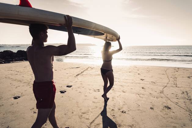 France, Brittany, young couple carrying an SUP board on the beach together model released Symbolfoto  UUF15917