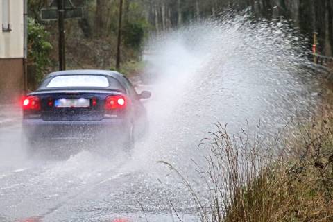 Dangerous road conditions during heavy rain The water from a road flooded after heavy rain is torn into the air by the cars and causes many drivers to be terrified Essen Nordrhein Westfalen Germany Deutschland Überruhr