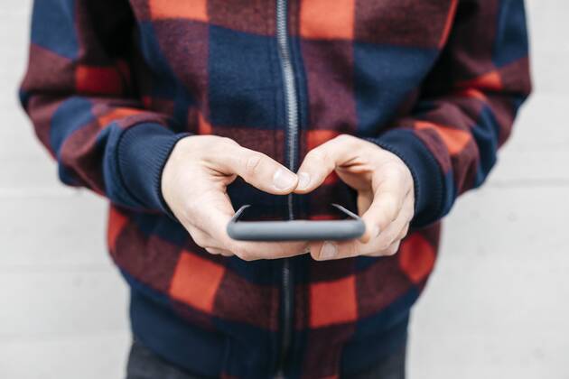 Hands of young man with chequered jacket using phone model released Symbolfoto  JRFF02561