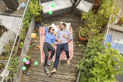 Young couple relaxing on their balcony, lying on blanket with arms around model released Symbolfoto property released  PESF01171