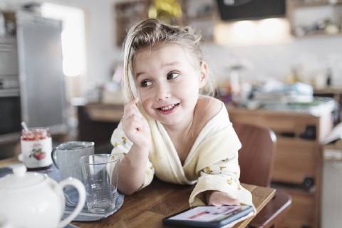 Portrait of smiling little girl with smartphone in the kitchen model released Symbolfoto property released  KMKF00721