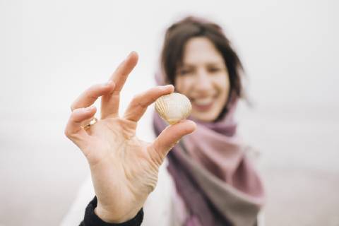 Woman s hand holding collected shell, close-up model released Symbolfoto  KMKF00754