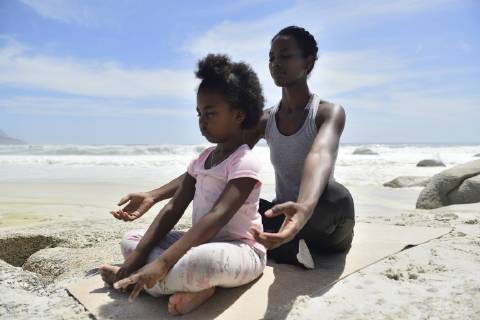 Mother with daughter doing a yoga exercise on the beach model released Symbolfoto  ECPF00395