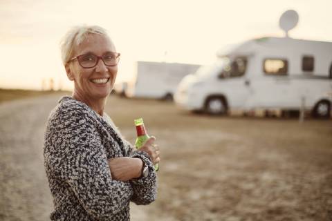 Portrait of smiling woman with beer bottle on camping ground in the evening model released Symbolfoto  JATF01136