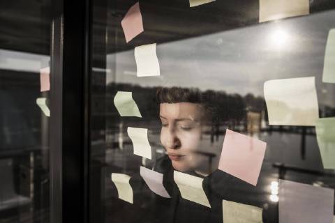 Tired woman leaning against window pane with sticky notes model released Symbolfoto property released  MJRF00107