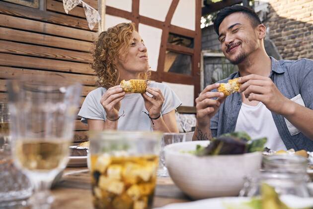 Couple eating grilled corn cobs at a backyard barbecue model released Symbolfoto property released  PDF01857