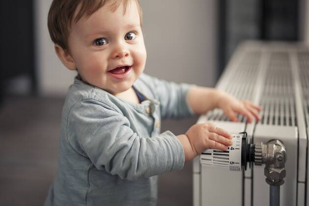 Portrait of smiling baby boy playing with thermostat of heater model released Symbolfoto property released  SEBF00022