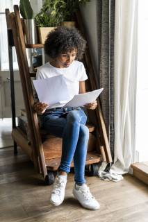 Woman sitting on steps at home looking at document model released Symbolfoto property released  GIOF05667