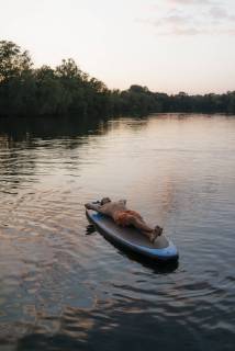 Man lying on SUP board on a lake at sunset model released Symbolfoto  GUSF01831