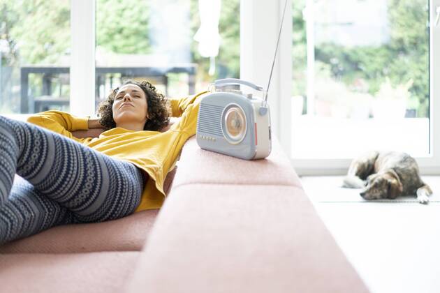 Woman lying on couch listening to music with portable radio at home model released Symbolfoto property released  JOSF02698