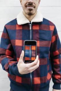 Young man showing a photo on the phone in the colors of his jacket model released Symbolfoto property released  JRFF02564