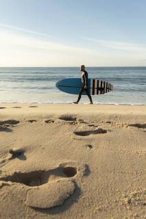 Spain, Andalusia, Tarifa, man walking with stand up paddle board on the beach model released Symbolfoto  KBF00368