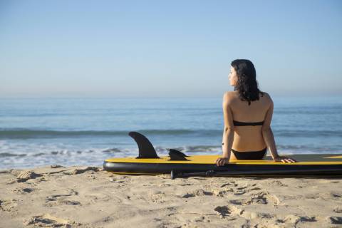 Spain, Andalusia, Tarifa, woman sitting on stand up paddle board on the beach model released Symbolfoto  KBF00393