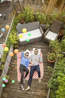 Young couple relaxing on their balcony, lying on blanket with arms around model released Symbolfoto property released  PESF01170