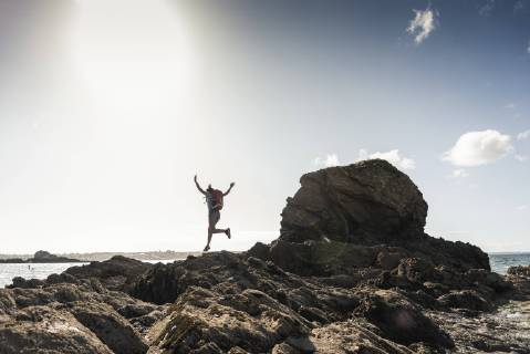 Young woman runnning and jumping on a rocky beach model released Symbolfoto  UUF16458