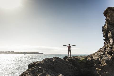 Young woman hiking on a rocky beach, looking at view model released Symbolfoto  UUF16462