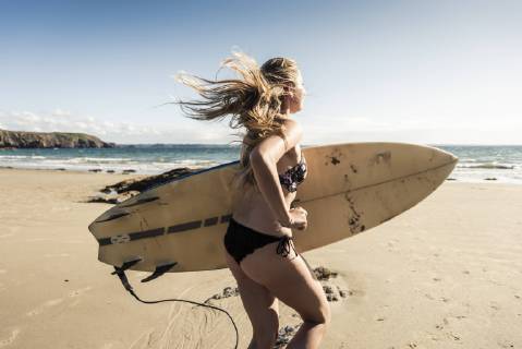Young woman running on the beach, carrying surfboard model released Symbolfoto  UUF16488