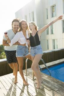 Friends having fun at a rooftop pool, drinking red wine model released Symbolfoto property released  VABF02112