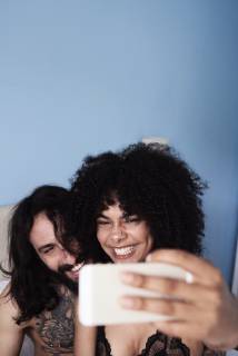 Happy affectionate young couple taking a selfie in bed model released Symbolfoto property released IGGF01069