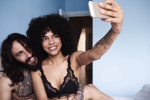 Happy affectionate young couple taking a selfie in bed model released Symbolfoto property released  IGGF01070