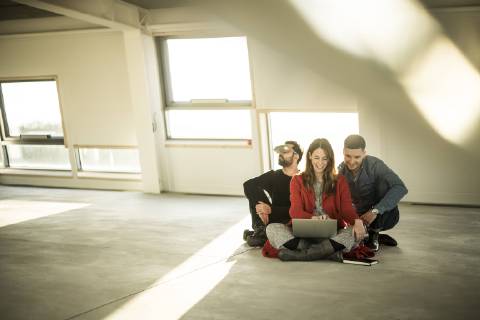 Colleagues sitting on floor of empty office rooms, making plans, using laptop and VR goggles model released Symbolfoto property released  MJRF00223